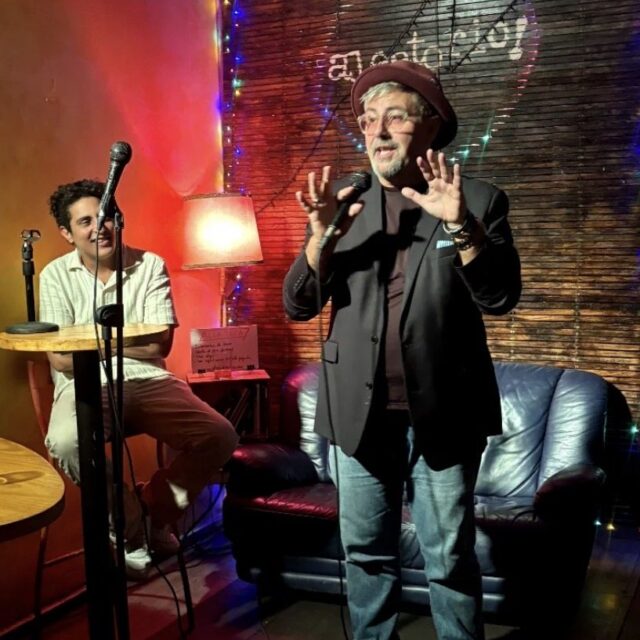 Comedian in a hat performing at a No Offense, But... show