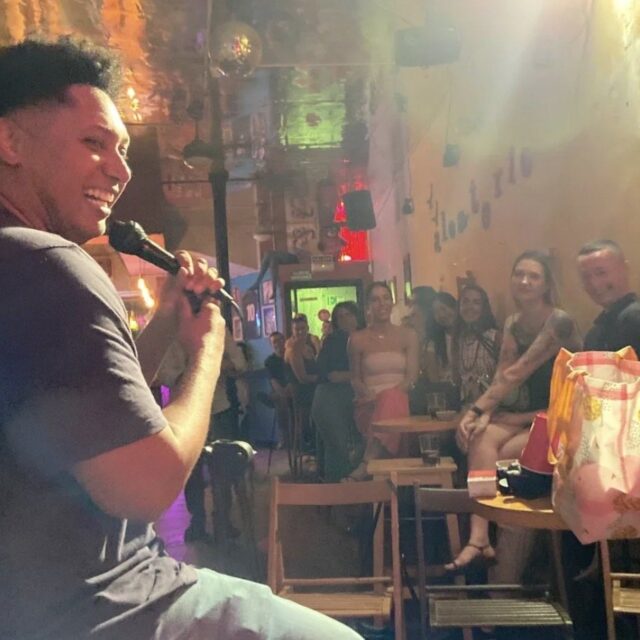 Comedian laughing into the microphone at a No Offense, But... show