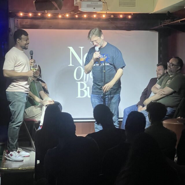 Comedian on stage under the projected No Offense, But... logo